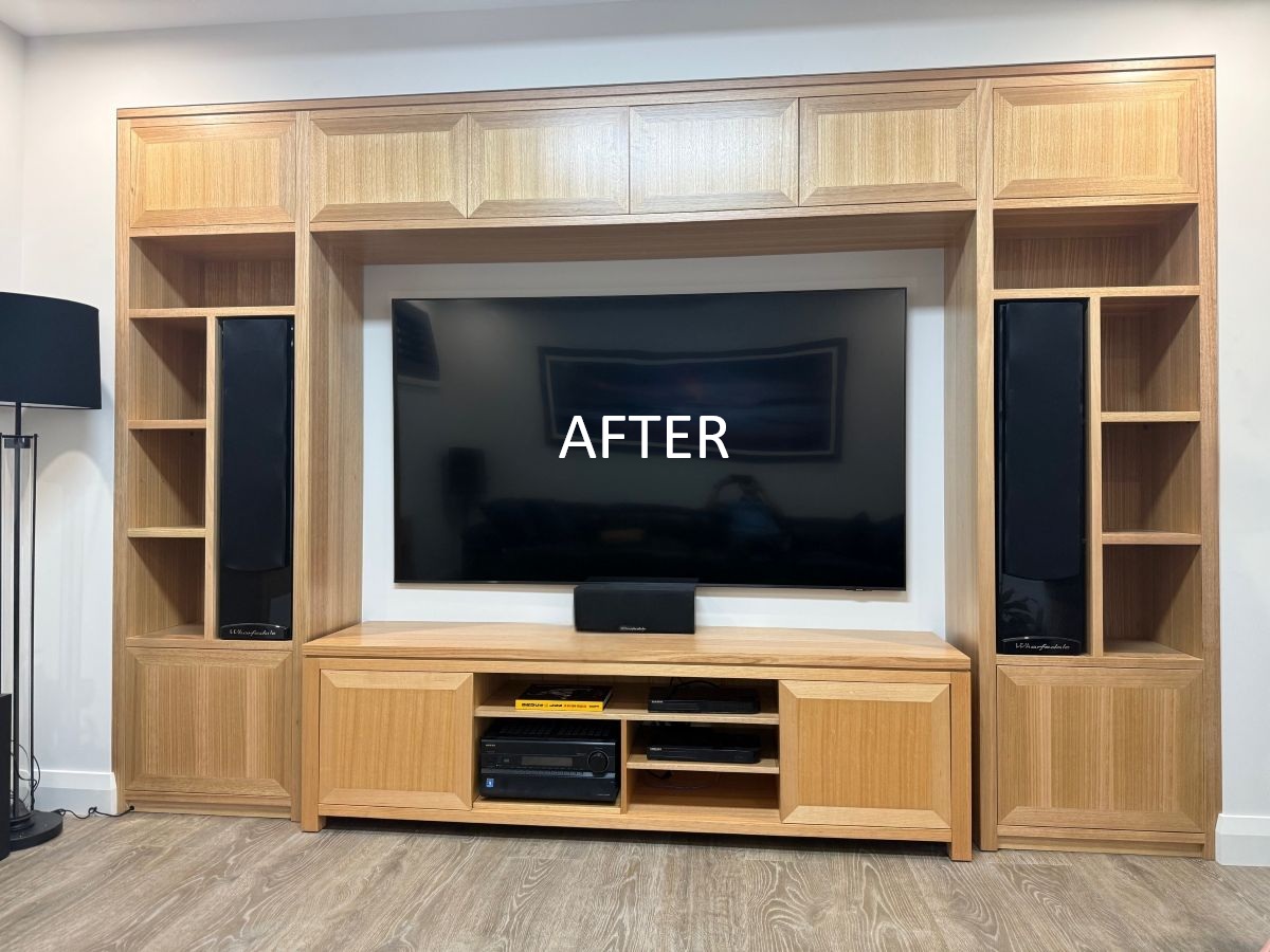 Modern wooden entertainment unit with a large flat-screen TV, flanked by black speakers and open shelving, showcasing a stylish interior design.