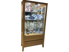 Display unit featuring glass shelves and LED lighting, showcasing decorative porcelain and glassware, suitable for personalized home decor.