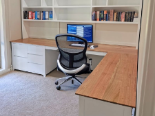 Custom-made office furniture setup featuring a wooden desk, ergonomic chair, and shelving with books, showcasing Coastal Design Furniture's tailored solutions for home offices.