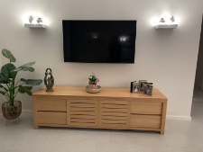 Custom made timber TV unit with storage drawers, decorative plant, and wall-mounted television, showcasing Coastal Design Furniture's bespoke furniture offerings.
